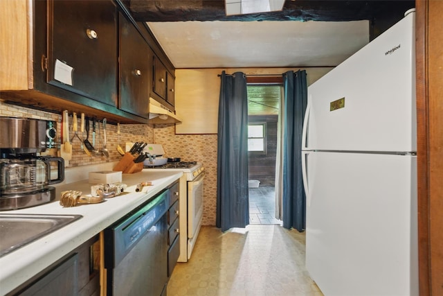 kitchen featuring white appliances, light countertops, under cabinet range hood, a sink, and decorative backsplash