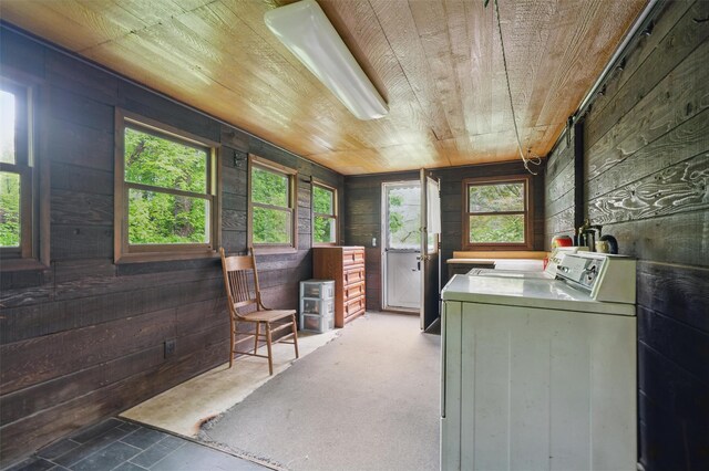 clothes washing area featuring washer / dryer, wooden ceiling, wooden walls, and a wood stove