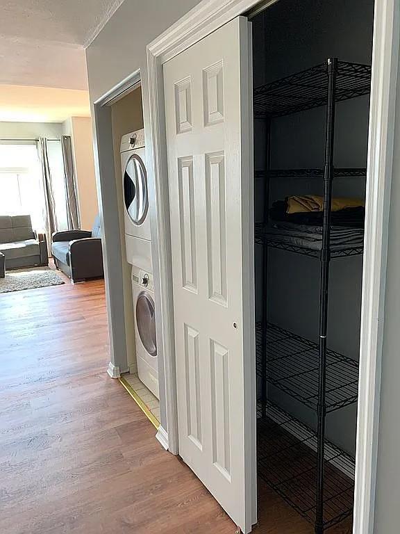 162 Commodore Cir E, Arverne, NY 11692 - laundry room featuring stacked washer and clothes dryer and wood finished floors