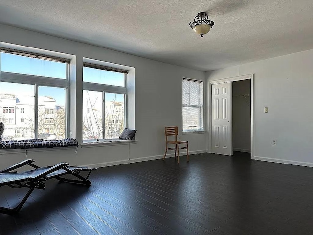 162 Commodore Cir E, Arverne, NY 11692 - unfurnished room featuring plenty of natural light, a textured ceiling, dark wood-type flooring, and baseboards