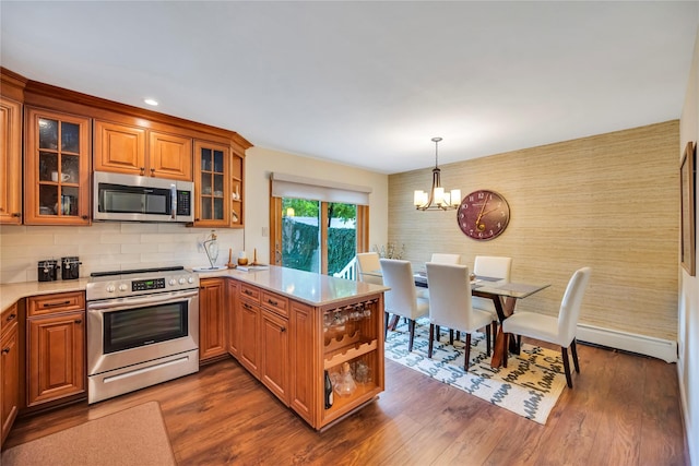 115 19th St, Wading River, NY 11792 - kitchen with stainless steel appliances, a peninsula, a chandelier, brown cabinetry, and recessed lighting