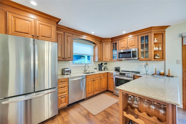 115 19th St, Wading River, NY 11792 - kitchen featuring stainless steel appliances, a sink, brown cabinetry, light wood-type flooring, and a peninsula