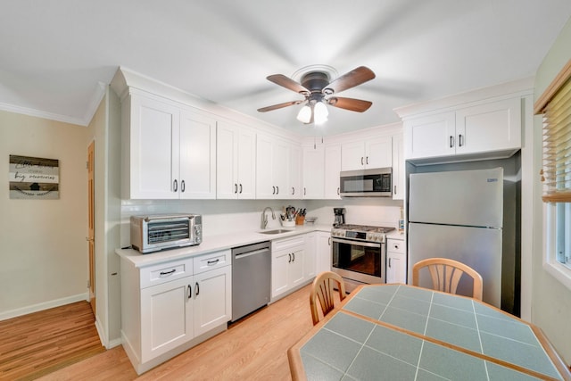 27 Columbus Ave, Kings Park, NY 11754 - kitchen with appliances with stainless steel finishes, white cabinetry, light wood-style floors, a ceiling fan, and ornamental molding