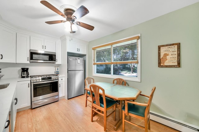 27 Columbus Ave, Kings Park, NY 11754 - kitchen with stainless steel appliances, a baseboard radiator, white cabinets, decorative backsplash, and light wood-style floors