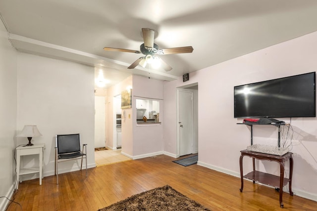 living area featuring hardwood / wood-style flooring, ceiling fan, and baseboards