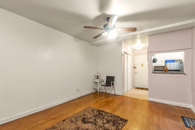 living area featuring ceiling fan, light wood-style floors, and baseboards