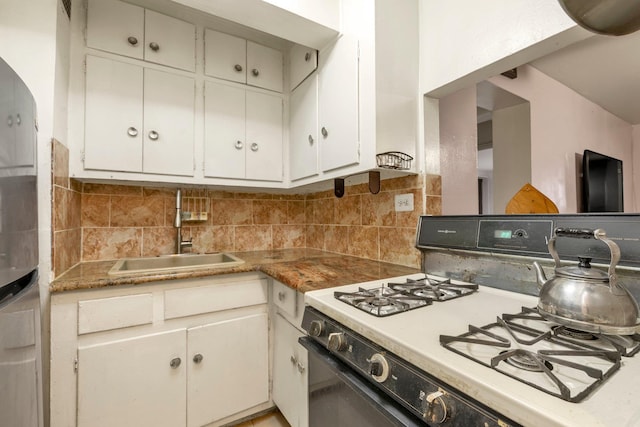 kitchen featuring gas range gas stove, a sink, decorative backsplash, and white cabinets