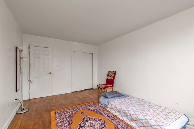 bedroom with wood finished floors, a closet, and baseboards