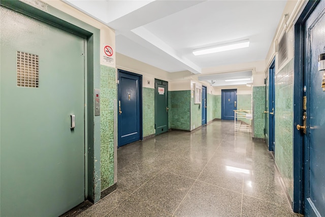 hallway featuring elevator and baseboards