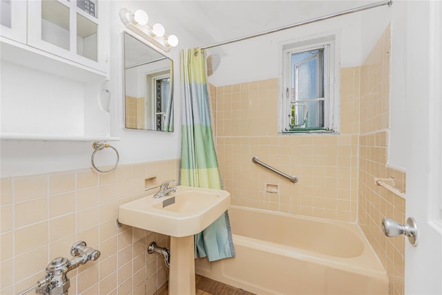 bathroom featuring tile walls and shower / bathtub combination with curtain