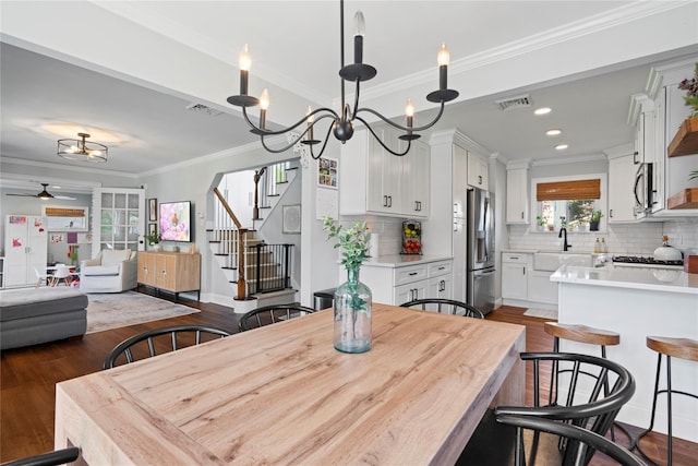 8 Vera Ct, West Islip, NY 11795 - dining space featuring dark wood-type flooring, a chandelier, a ceiling fan, crown molding, and stairs