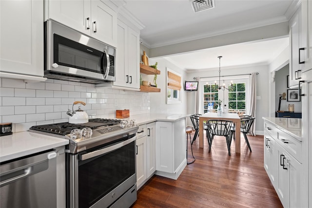 8 Vera Ct, West Islip, NY 11795 - kitchen featuring appliances with stainless steel finishes, light countertops, dark wood-style flooring, white cabinetry, and ornamental molding