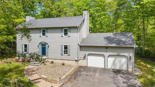 50 Maple Wood Dr, Brewster, NY 10509 - colonial home with a chimney, an attached garage, driveway, roof with shingles, and view of wooded area
