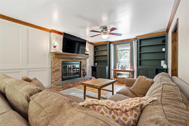 50 Maple Wood Dr, Brewster, NY 10509 - living room with a decorative wall, a fireplace, ceiling fan, wood finished floors, and crown molding