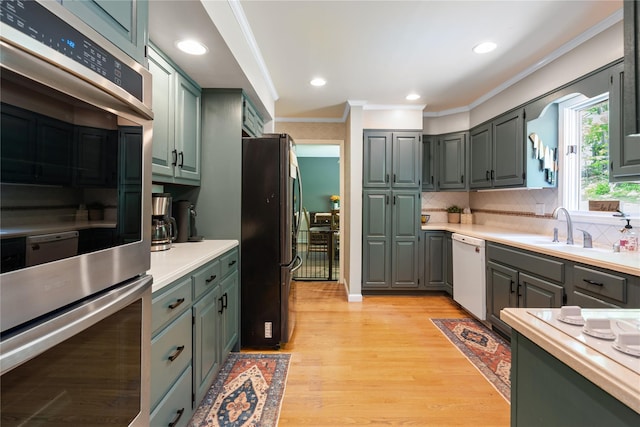 50 Maple Wood Dr, Brewster, NY 10509 - kitchen with stainless steel appliances, crown molding, a sink, light wood-style floors, and decorative backsplash