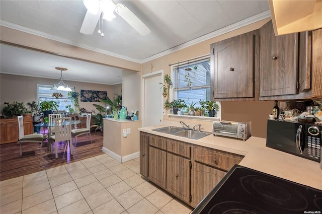 kitchen featuring black appliances, a sink, light countertops, crown molding, and light tile patterned flooring