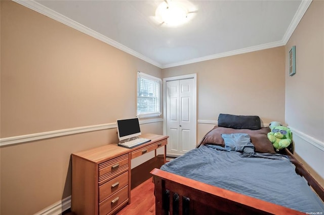 bedroom with crown molding, a closet, light wood-type flooring, a desk, and baseboards