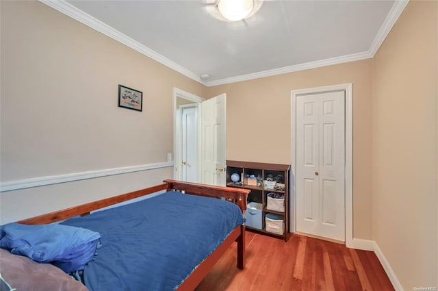 bedroom with wood finished floors, crown molding, and baseboards