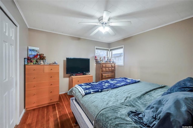 bedroom featuring dark wood-style flooring, crown molding, ceiling fan, baseboards, and a closet