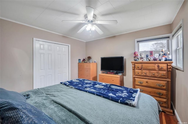 bedroom with wood finished floors, ornamental molding, a closet, and a ceiling fan