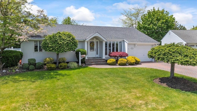 view of front of home featuring an attached garage, a front yard, decorative driveway, and roof with shingles