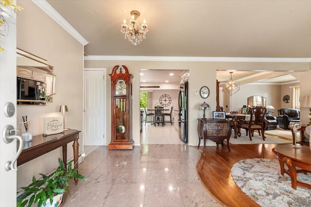 entryway featuring a chandelier, crown molding, and baseboards