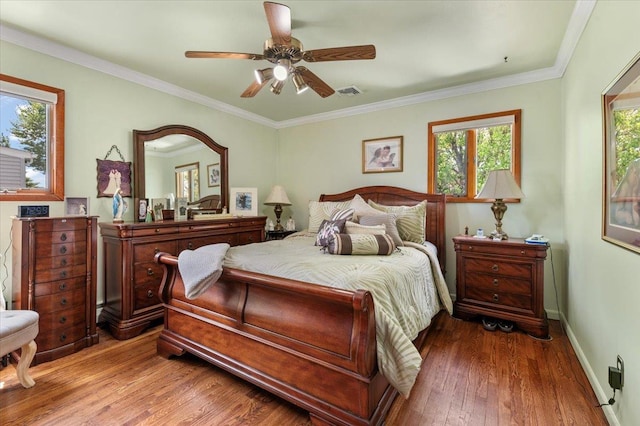 bedroom featuring wood-type flooring, baseboards, ornamental molding, and a ceiling fan