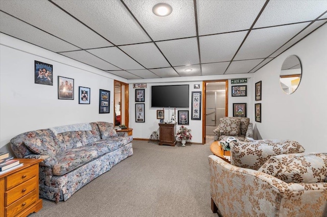 carpeted living area featuring a paneled ceiling and baseboards