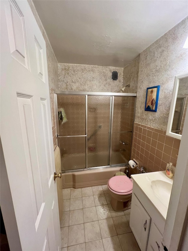 86-10 151st Ave Unit 4G, Howard Beach, NY 11414 - bathroom with tile walls, bath / shower combo with glass door, tile patterned floors, vanity, and toilet