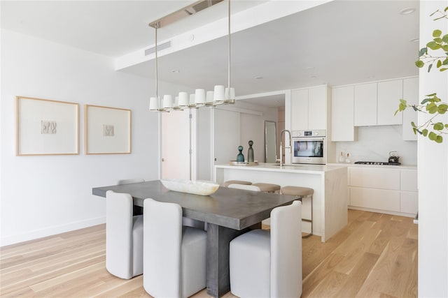 dining room featuring light wood-style flooring and baseboards