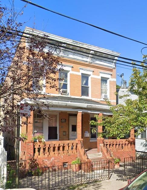 view of front of house featuring brick siding, a porch, and a fenced front yard