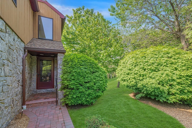 entrance to property with stone siding and a yard