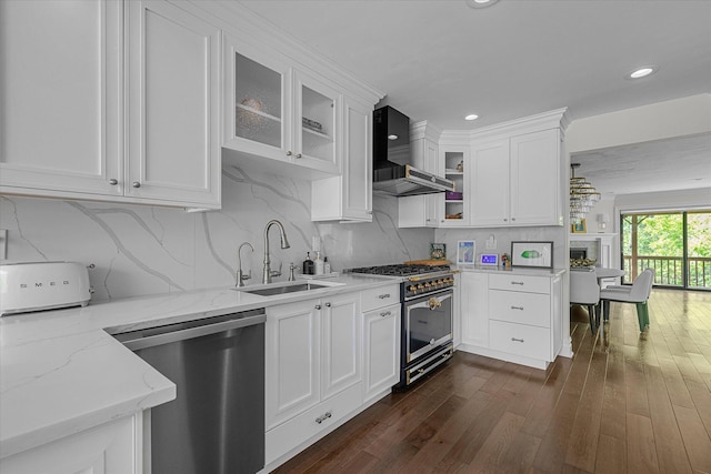 kitchen with appliances with stainless steel finishes, a sink, wall chimney range hood, white cabinetry, and recessed lighting