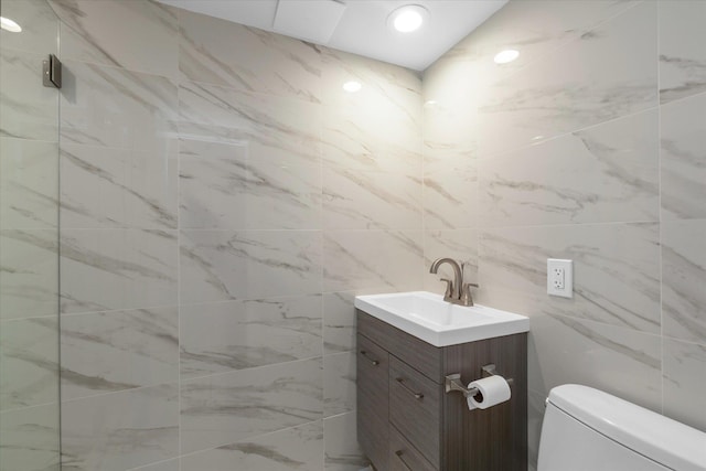 bathroom featuring toilet, vanity, and tile walls