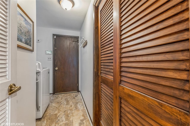 laundry room featuring washer and dryer, stone finish floors, and baseboards