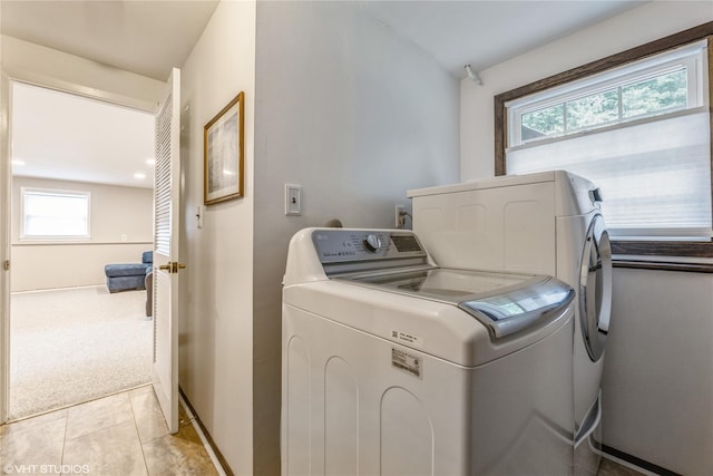 laundry area featuring separate washer and dryer, light tile patterned floors, light carpet, and baseboards