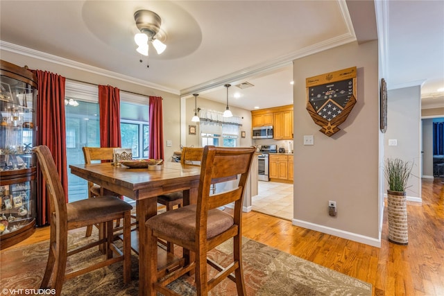 dining room with ornamental molding, a ceiling fan, light wood finished floors, and baseboards