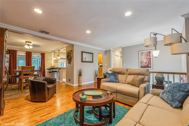 living room featuring ornamental molding, light wood-style floors, baseboards, recessed lighting, and ceiling fan