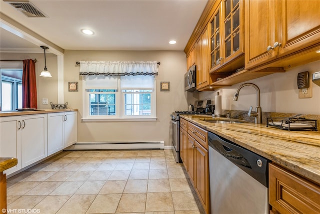 kitchen with stainless steel appliances, a baseboard heating unit, brown cabinets, a sink, and light stone countertops