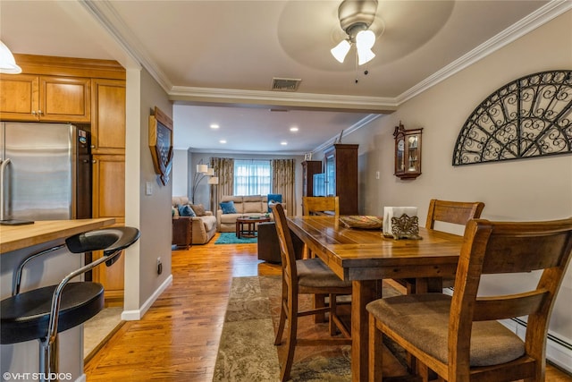 dining area featuring ornamental molding, light wood-style flooring, a ceiling fan, baseboards, and recessed lighting