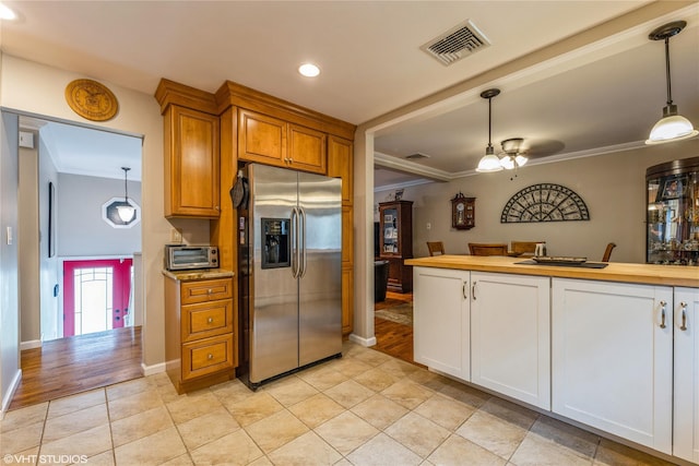 kitchen with stainless steel refrigerator with ice dispenser, ornamental molding, hanging light fixtures, recessed lighting, and baseboards