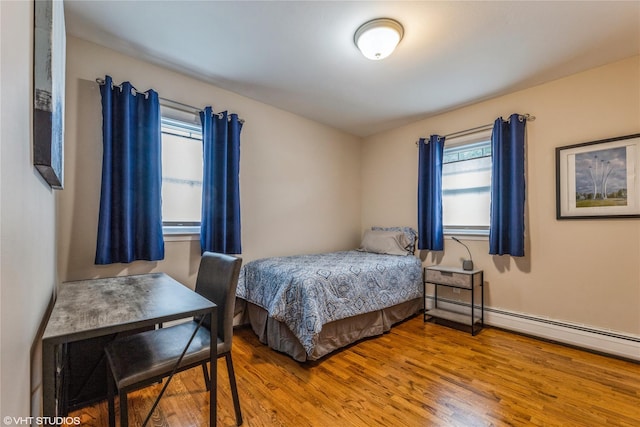 bedroom with wood finished floors and baseboard heating