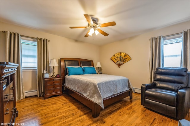 bedroom with wood finished floors, baseboard heating, and a ceiling fan