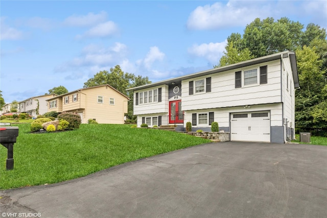 bi-level home with an attached garage, a front yard, driveway, and central AC