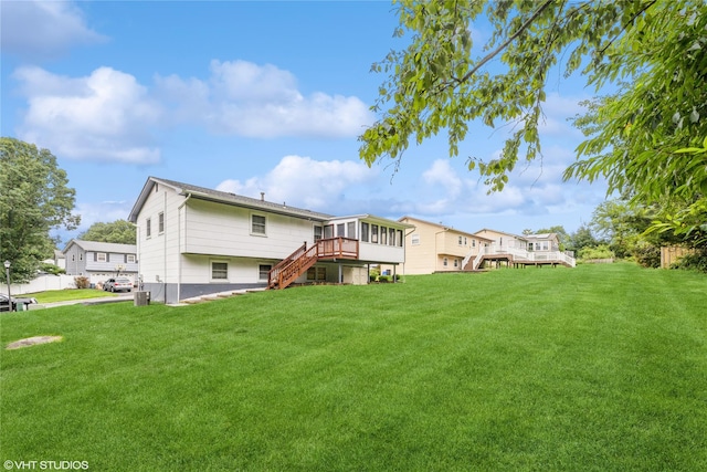 back of property with stairs, a wooden deck, and a lawn