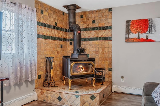 detailed view of a baseboard heating unit, a wood stove, and wood finished floors
