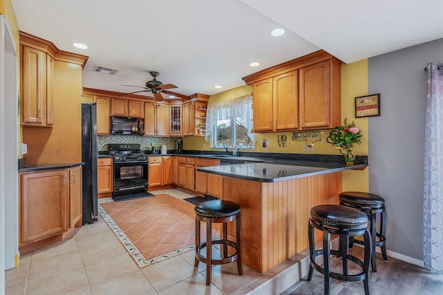 kitchen with black appliances, a peninsula, dark countertops, a ceiling fan, and recessed lighting