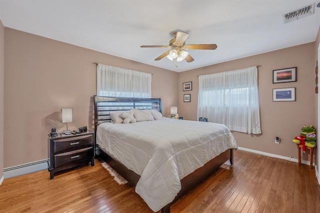 bedroom with light wood-style flooring, baseboards, baseboard heating, and a ceiling fan