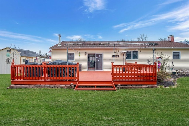 back of property with a wooden deck, a lawn, and a chimney