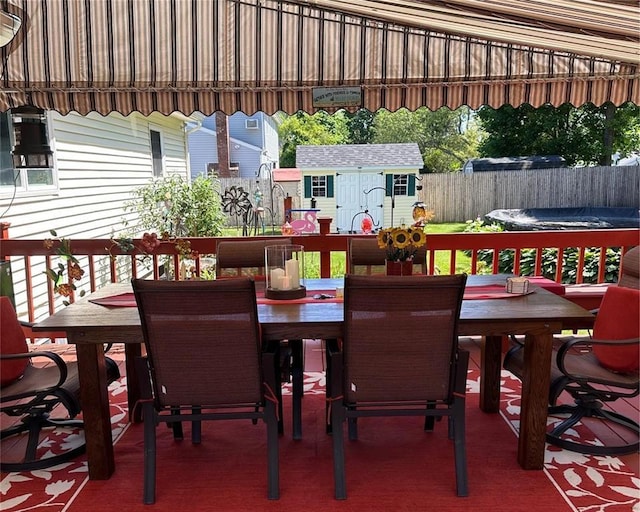 wooden deck featuring outdoor dining space, a shed, an outbuilding, and a fenced backyard
